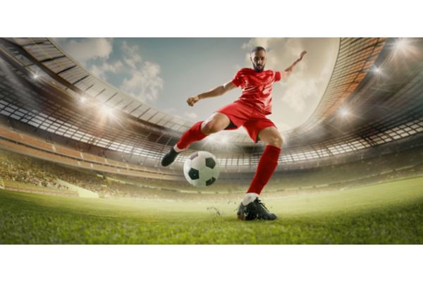 Soccer player kicking ball in red uniform
